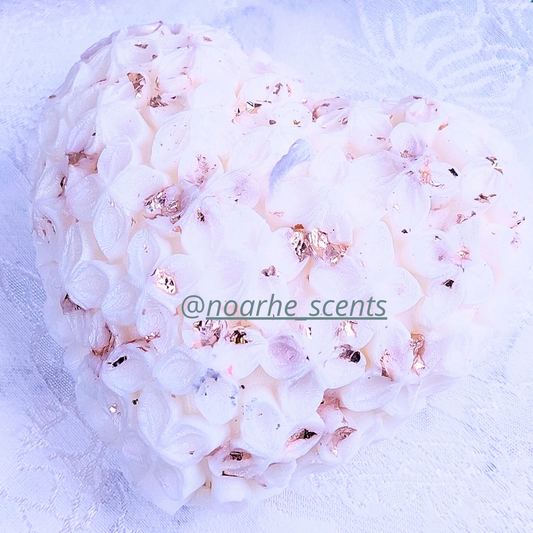 La vela perfecta para los enamorados, encenderá los sentidos con su encanto. Su delicada forma de corazón, decorada con pequeñas flores y chispas de pan de oro, la convierte en el complemento perfecto de veladas&nbsp;mágicas y románticas.

Puedes personalizarla en el color que prefieras, con o sin aroma.